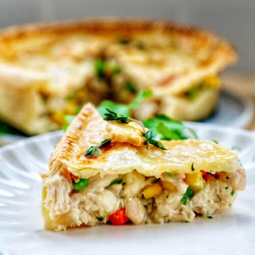 slice of air fryer chicken pot pie on a plate with a full chicken pot pie behind it.