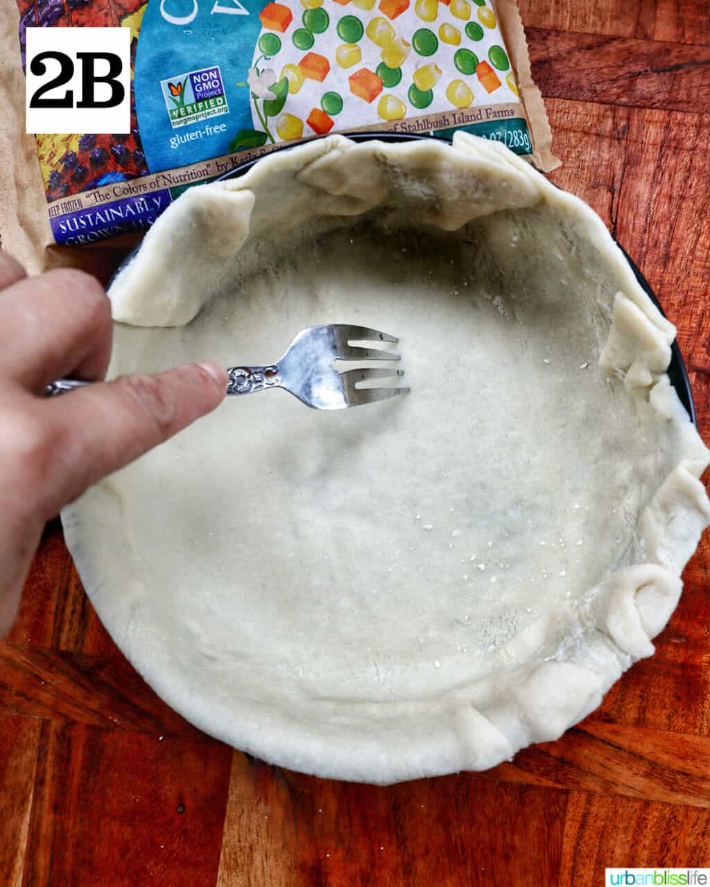hand poking the botto of pie crust with the times of a fork.