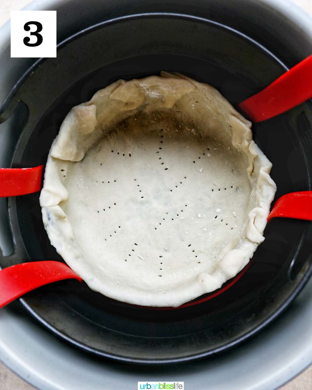 unbaked pie crust in a baking pan lowered into an air fryer basket.