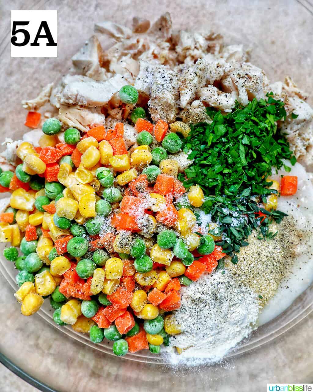 shredded chicken, mixed vegetables, and fresh herbs and seasonings in a large mixing bowl.