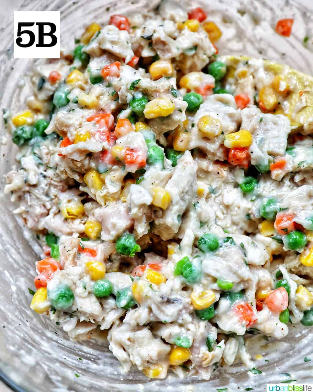 shredded chicken, mixed vegetables, and fresh herbs and seasonings in a large mixing bowl.