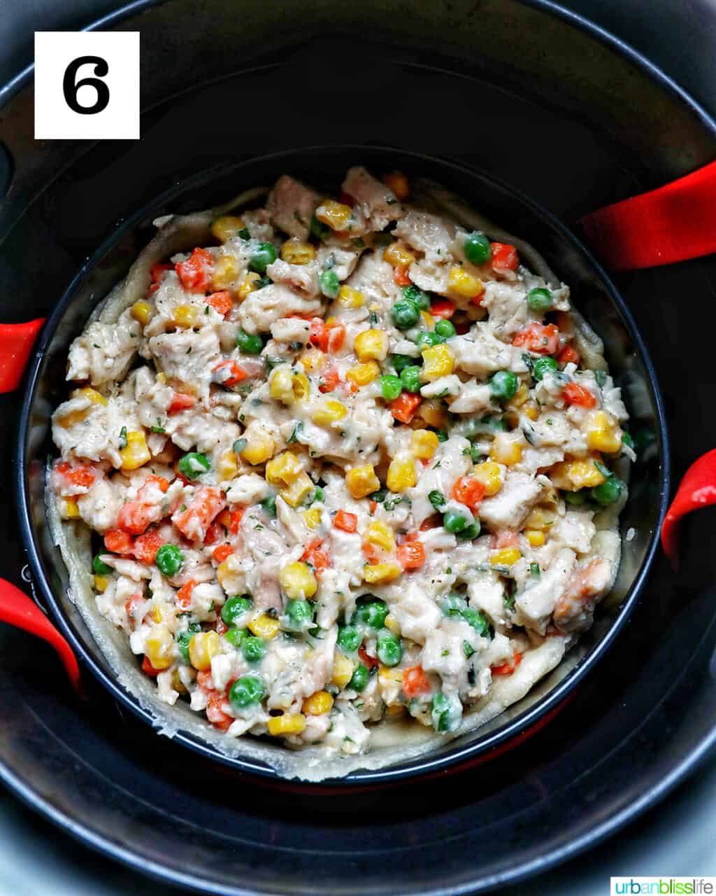 shredded chicken, mixed vegetables, and fresh herbs and seasonings in a baking pan lowered into an air fryer basket.