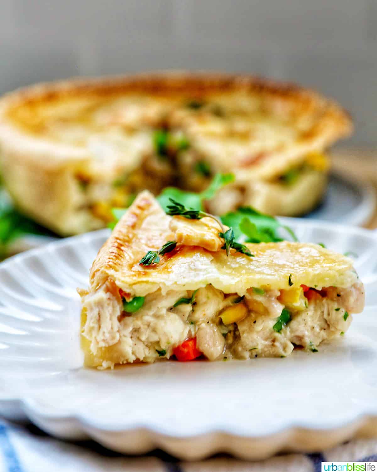 slice of air fryer chicken pot pie on a plate with a full chicken pot pie behind it.