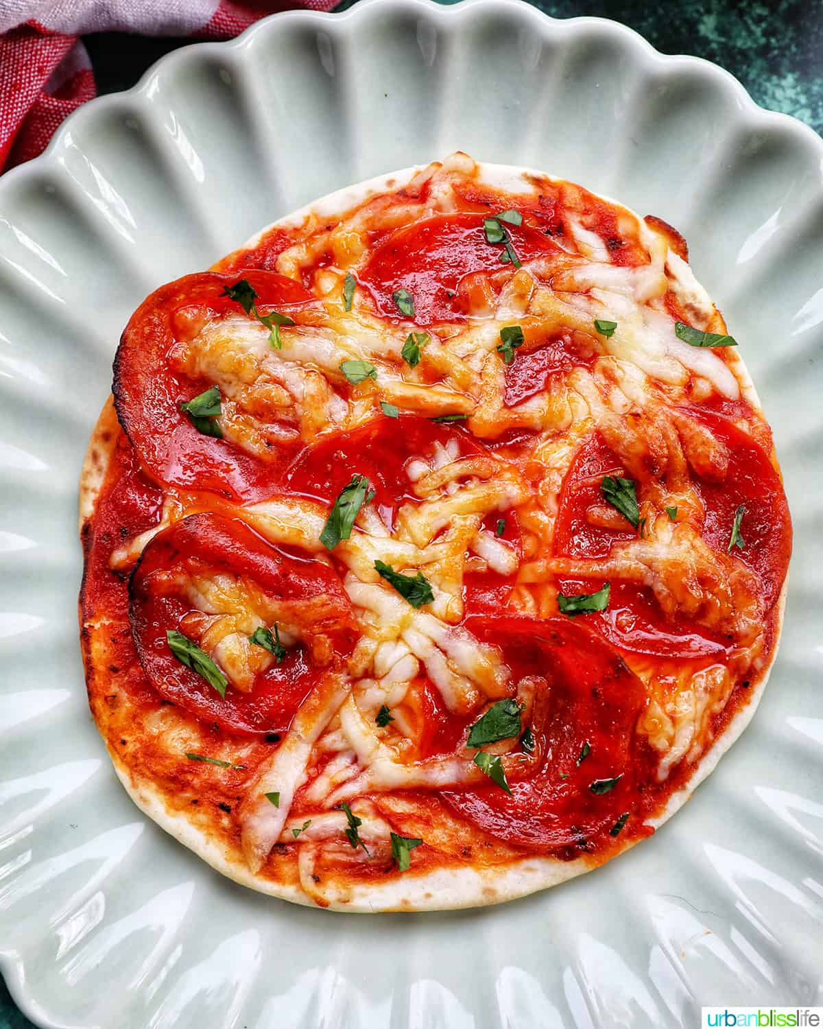 single air fryer mini pepperoni pizza on a scalloped plate.
