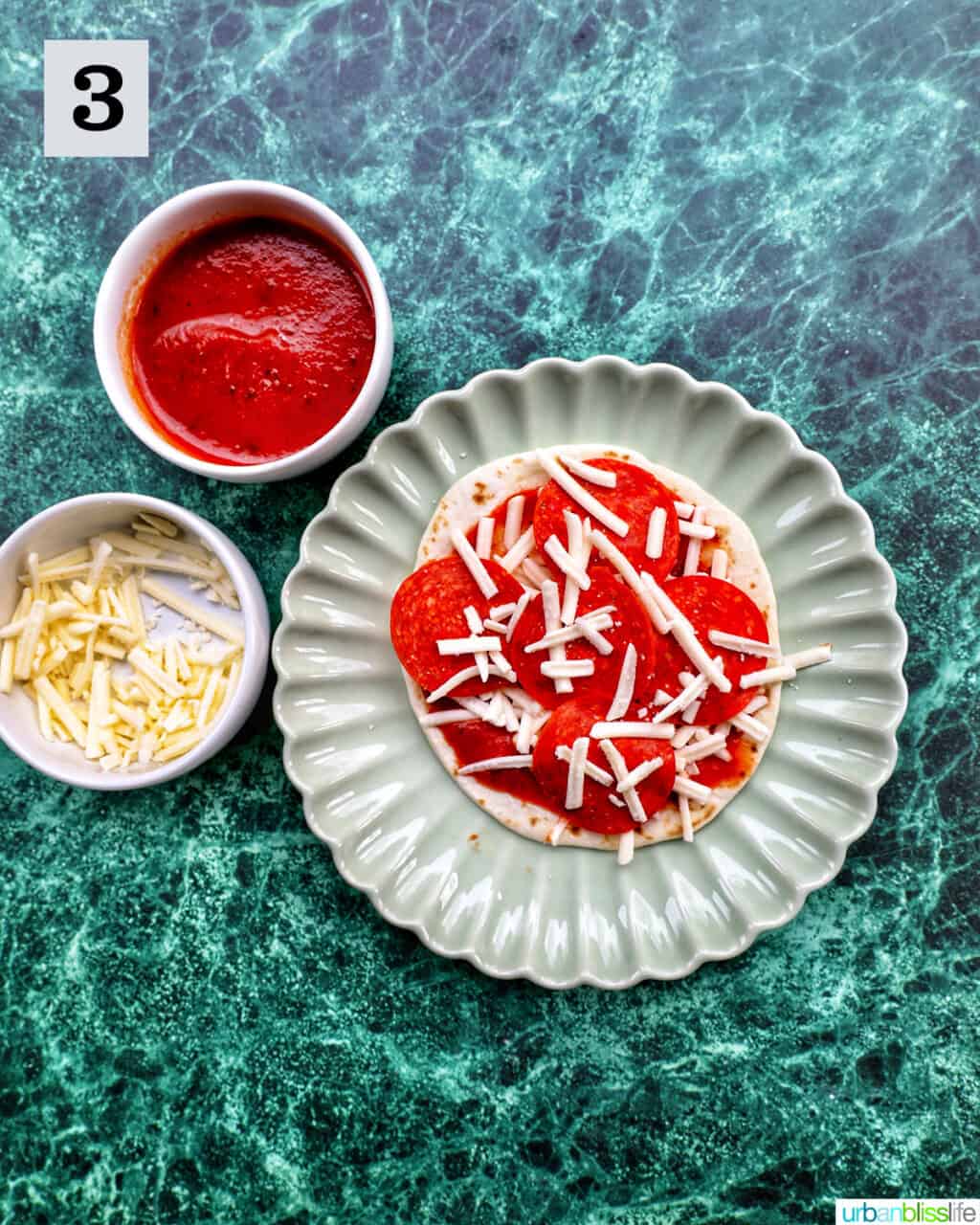 plate of a tortilla round with pizza sauce and shredded mozzarella.