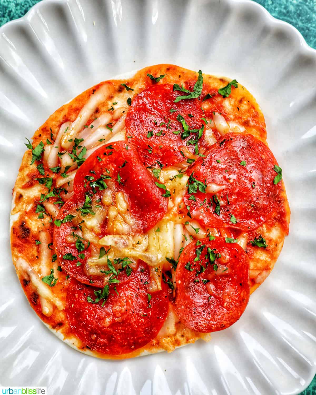 single air fryer mini pepperoni pizza on a scalloped plate.