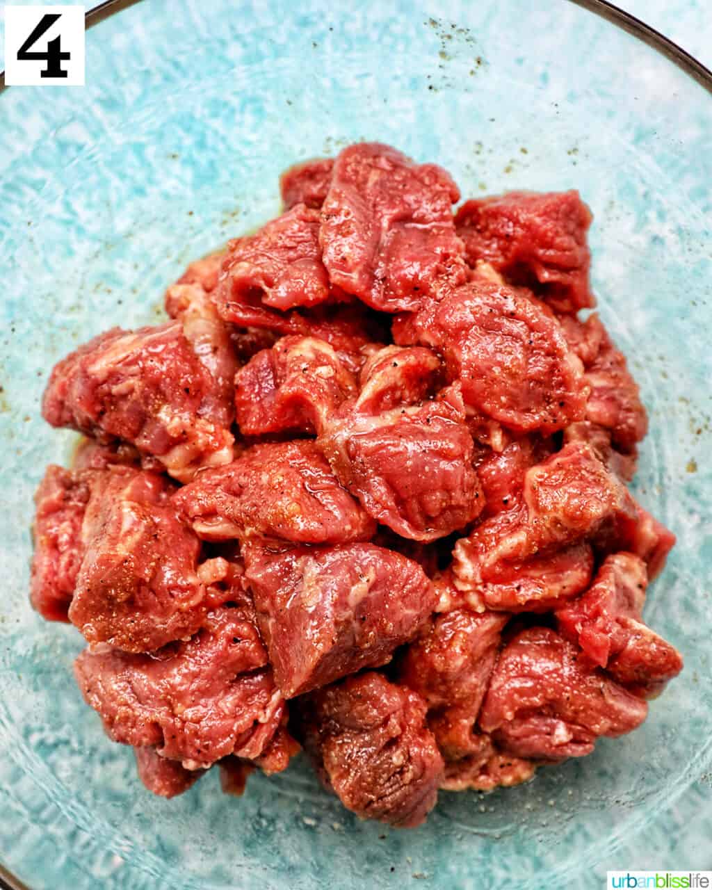 steak tips seasoned in a glass bowl.