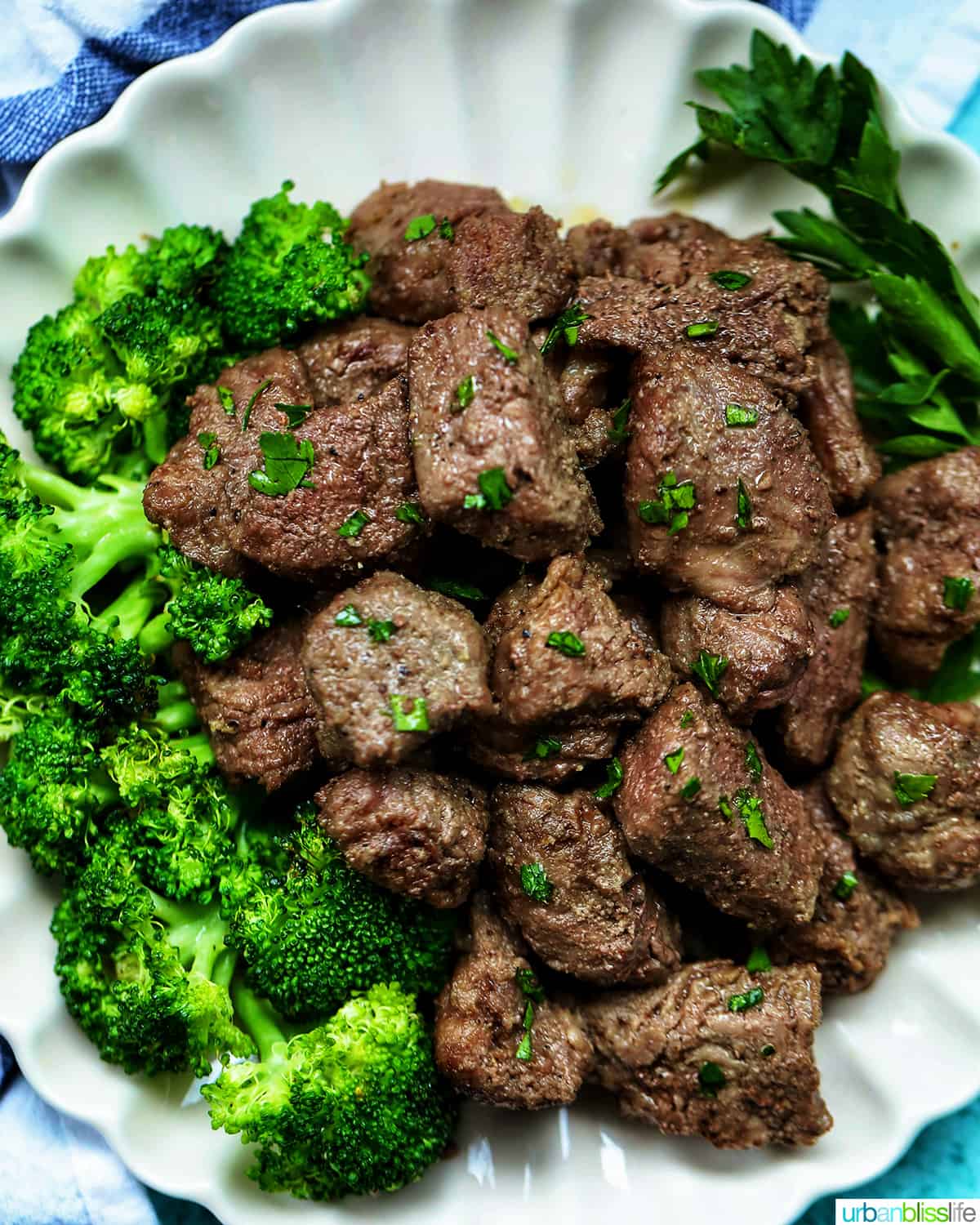 air fryer steak bites with chopped parsley garnish and a side of broccoli on a plate.