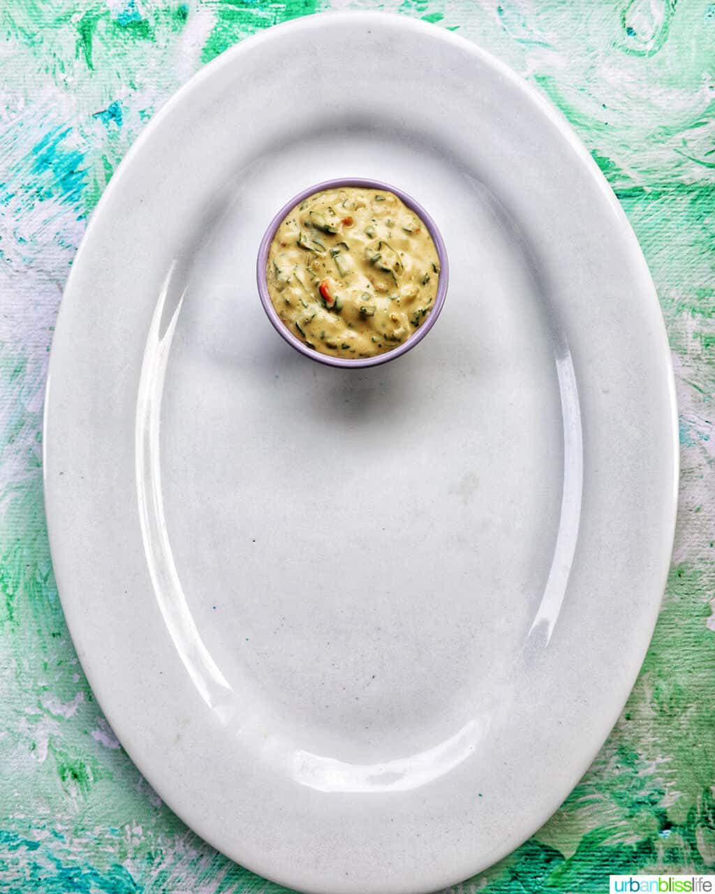 bowl of vegetable dip on a large white platter.