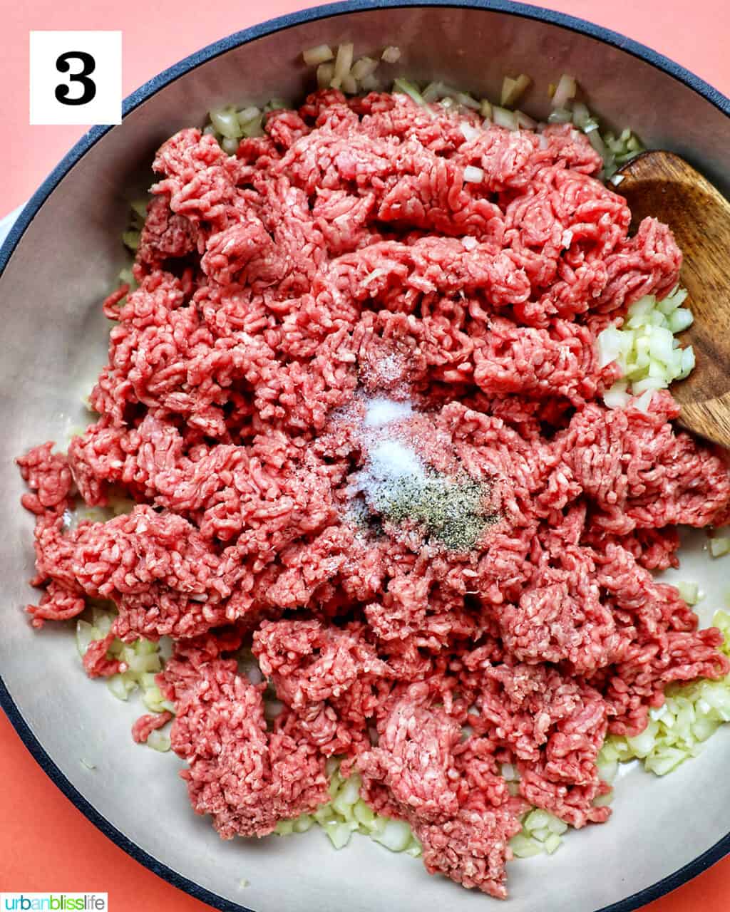 ground beef with salt and pepper in a large white pan.