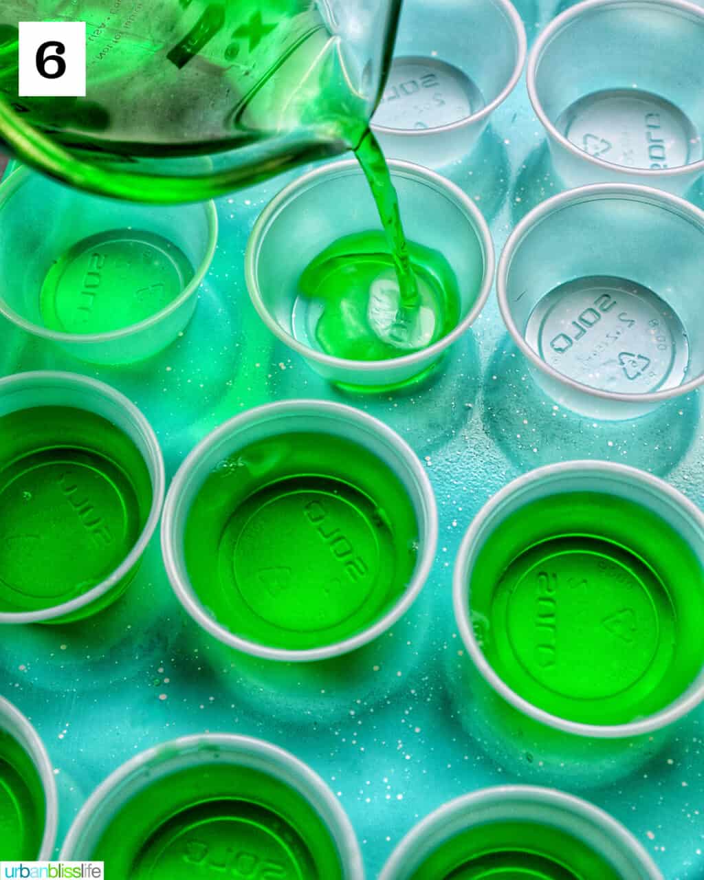 pouring green jello shot liquid into small shot cups.