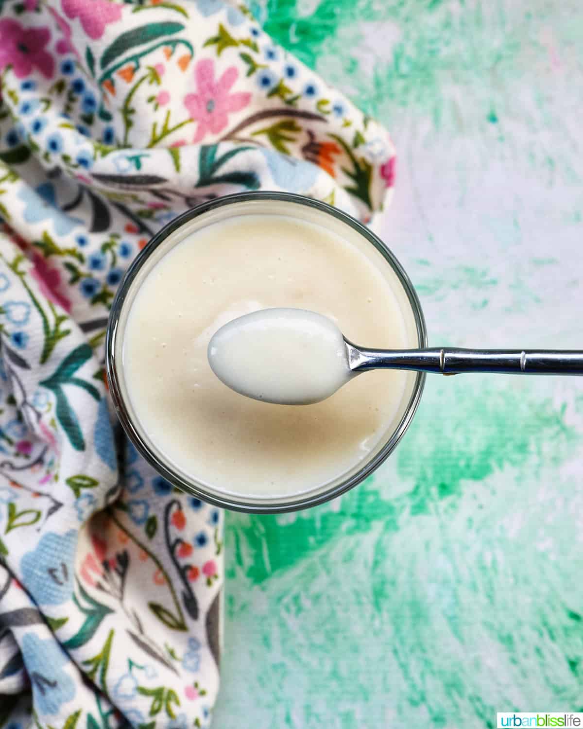 spoon with pudding above a parfait bowl with homemade vanilla pudding.