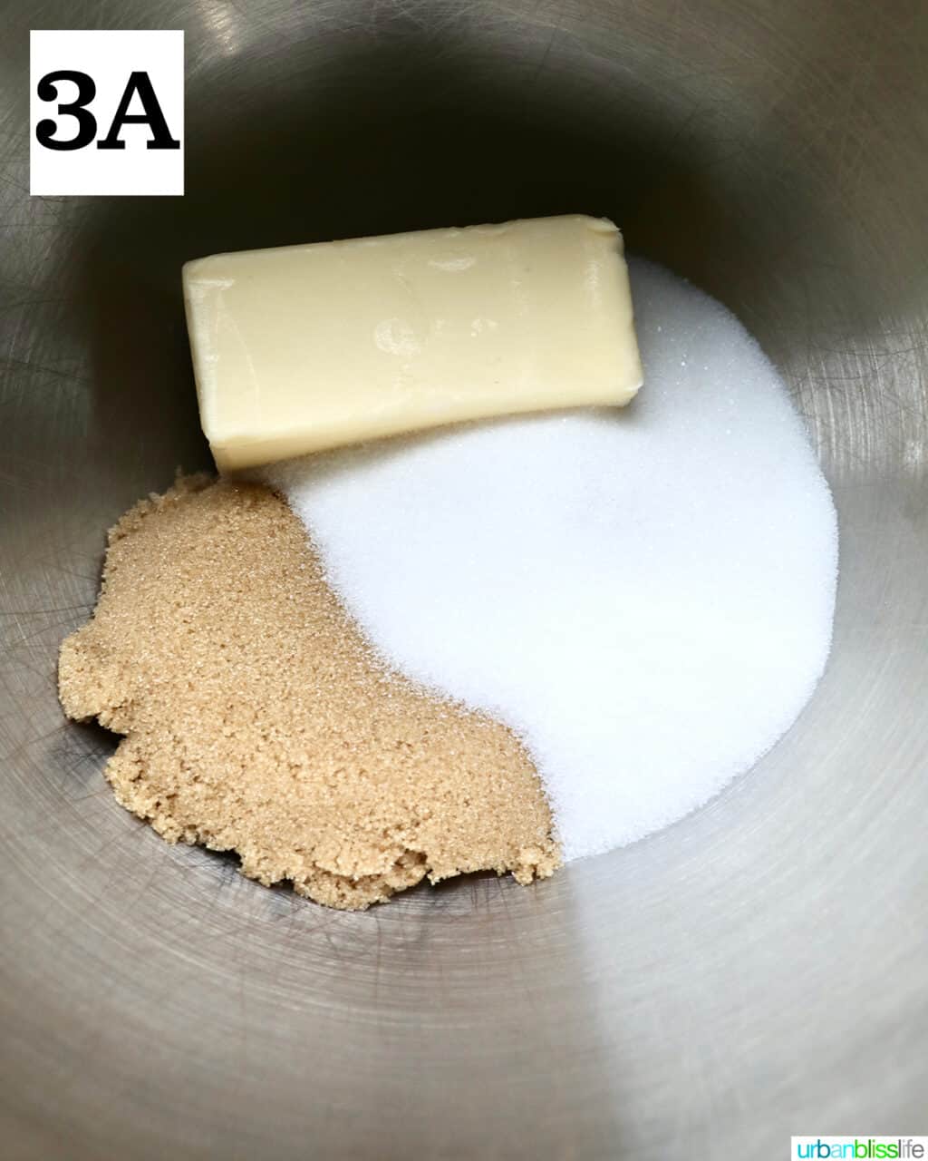 stick of butter, granulated sugar, and brown sugar in a stainless steel bowl.