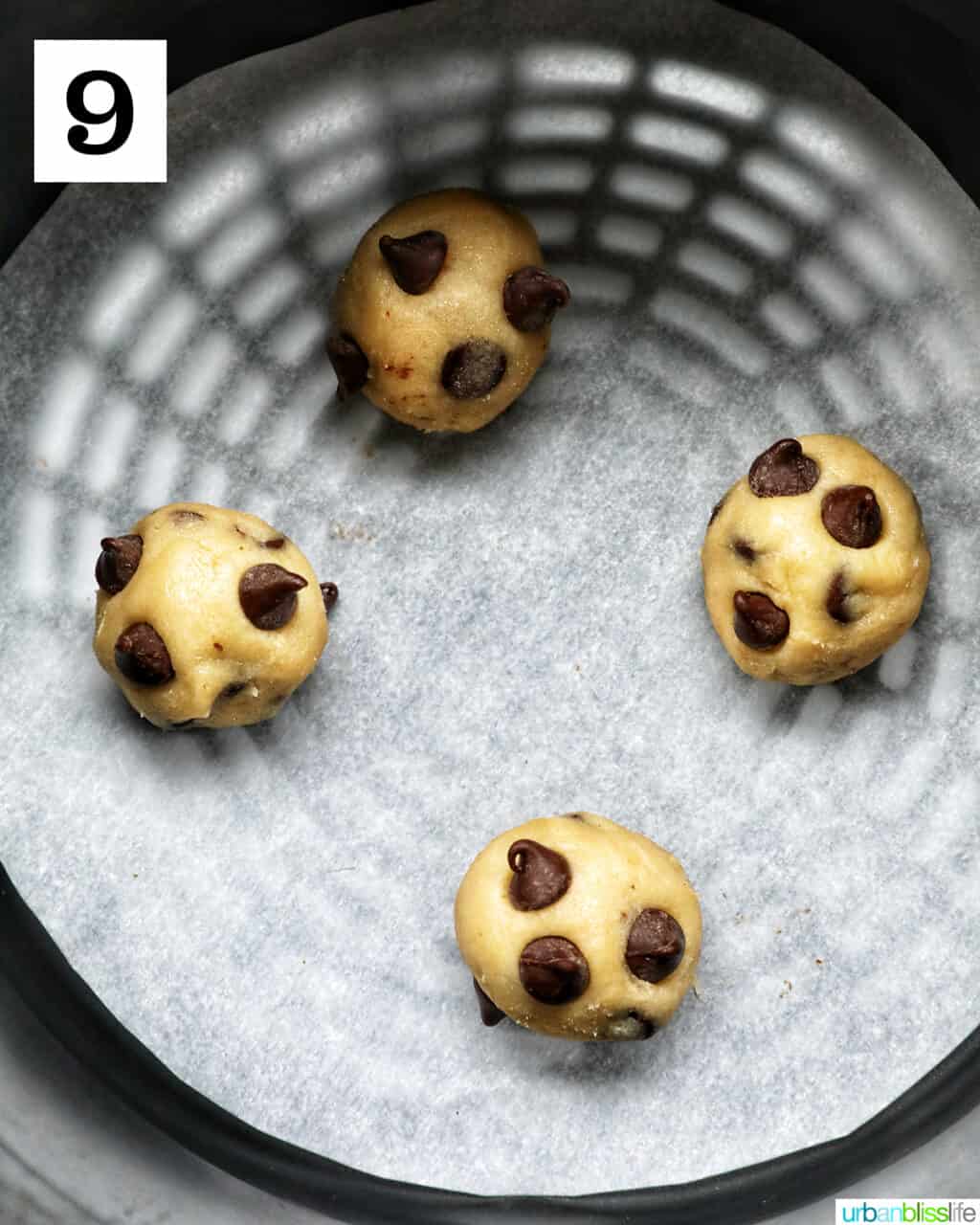 four chocolate chip cookie dough balls in an air fryer basket