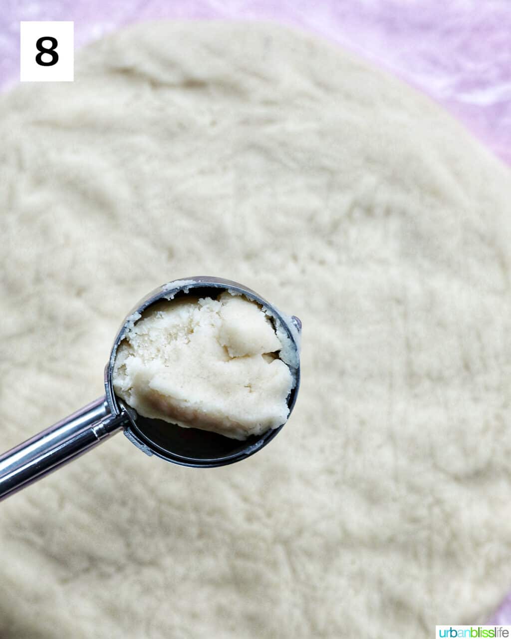 cookie scoop with cookie dough in it over a round of cookie dough.