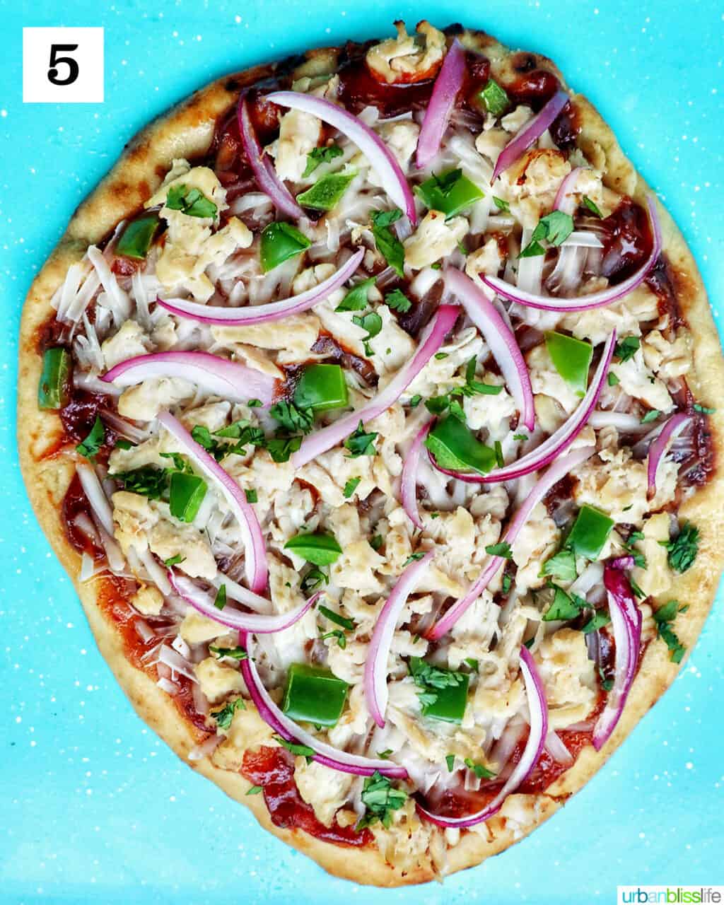 Baked barbecue chicken flatbread pizza on a blue baking sheet.