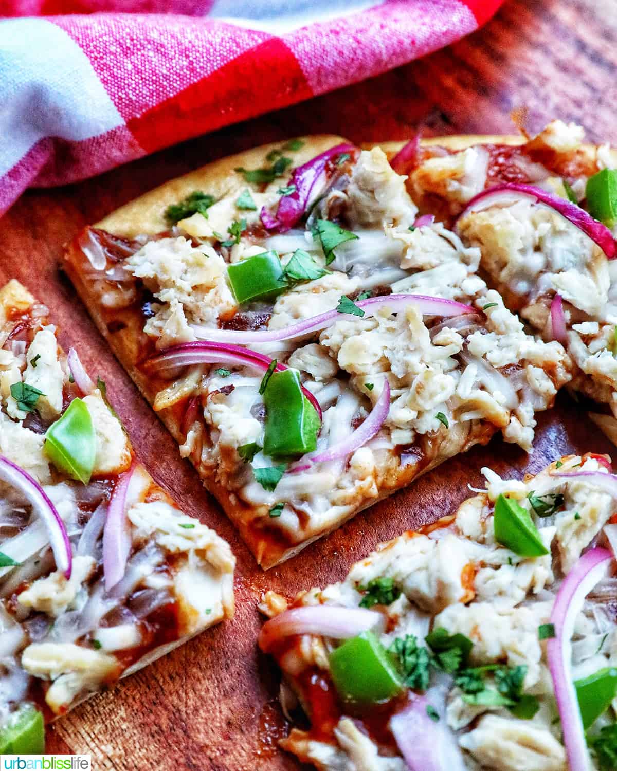 slices of bbq chicken flatbread with red onions, chicken breast, green peppers, and cilantro.