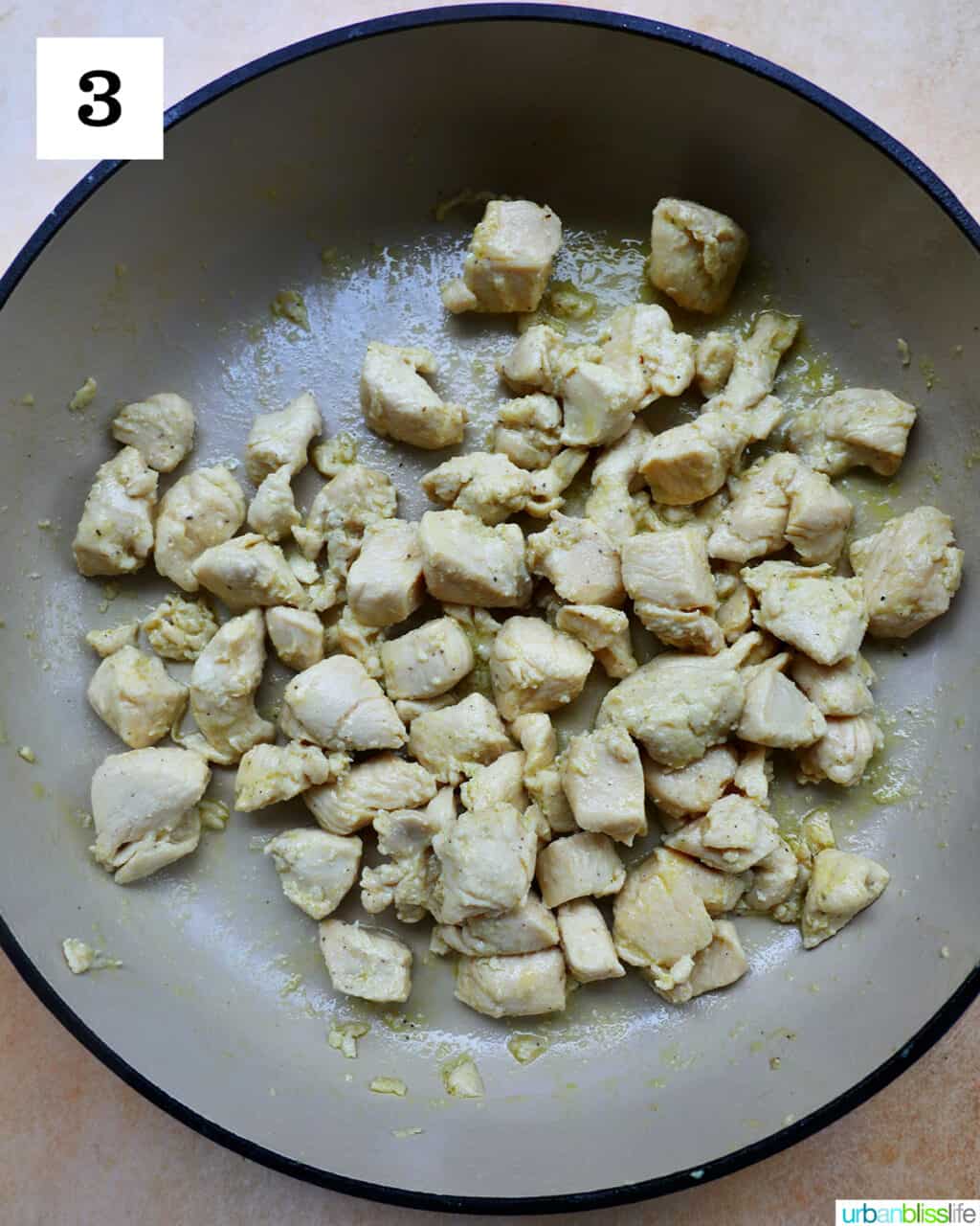 chunks of chicken cooking in olive oil in a large skillet.