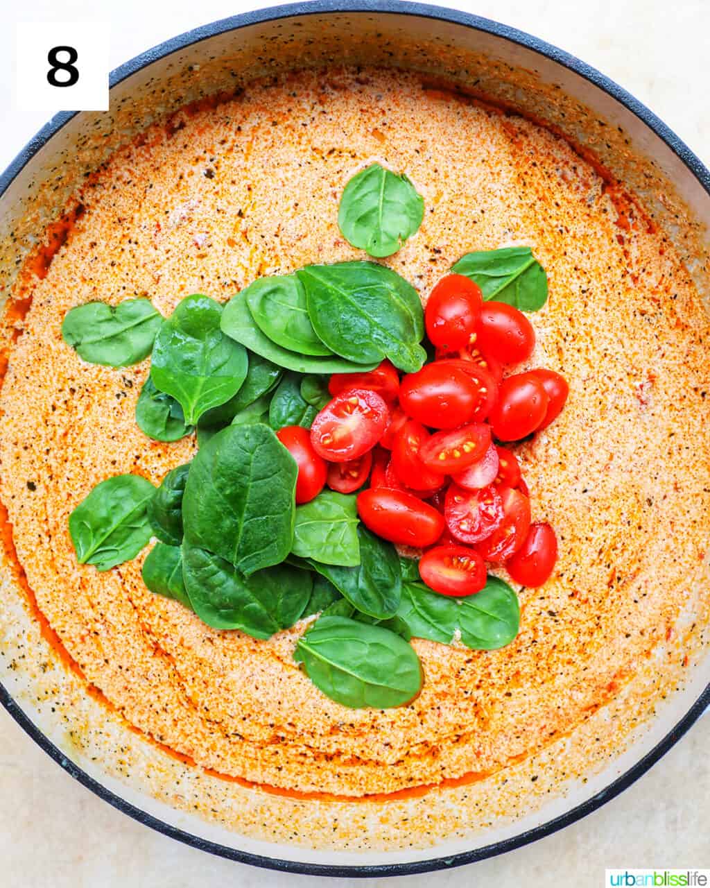 fresh spinach leaves and chopped cherry tomatoes over sun-dried tomato cream sauce in a large skillet.