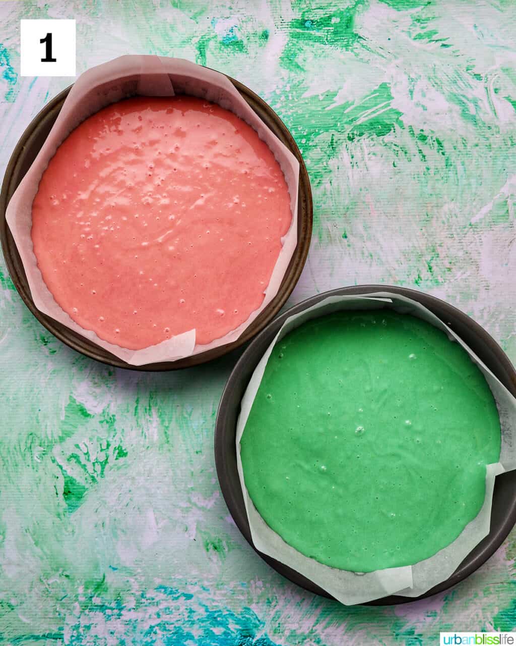 pink cake batter and green cake batter in round baking pans.