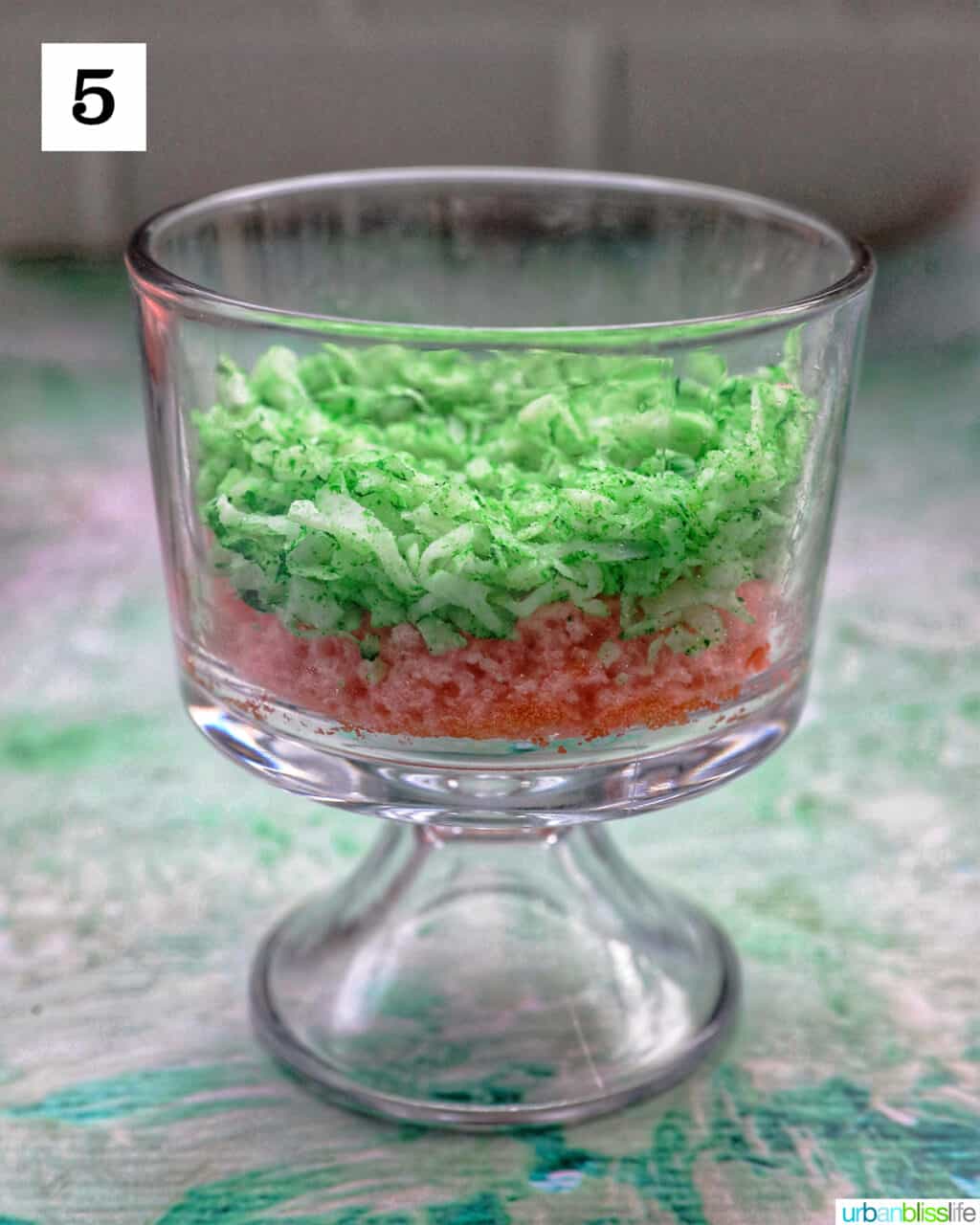 shredded coconut on a layer of pink cake in a trifle bowl.