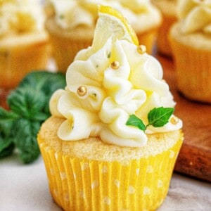 lemon basil cupcake with lemon buttercream frosting and garnish of basil leaves and lemon slice.