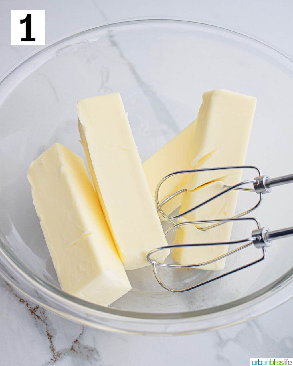 electric mixer with butter sticks n a large bowl.