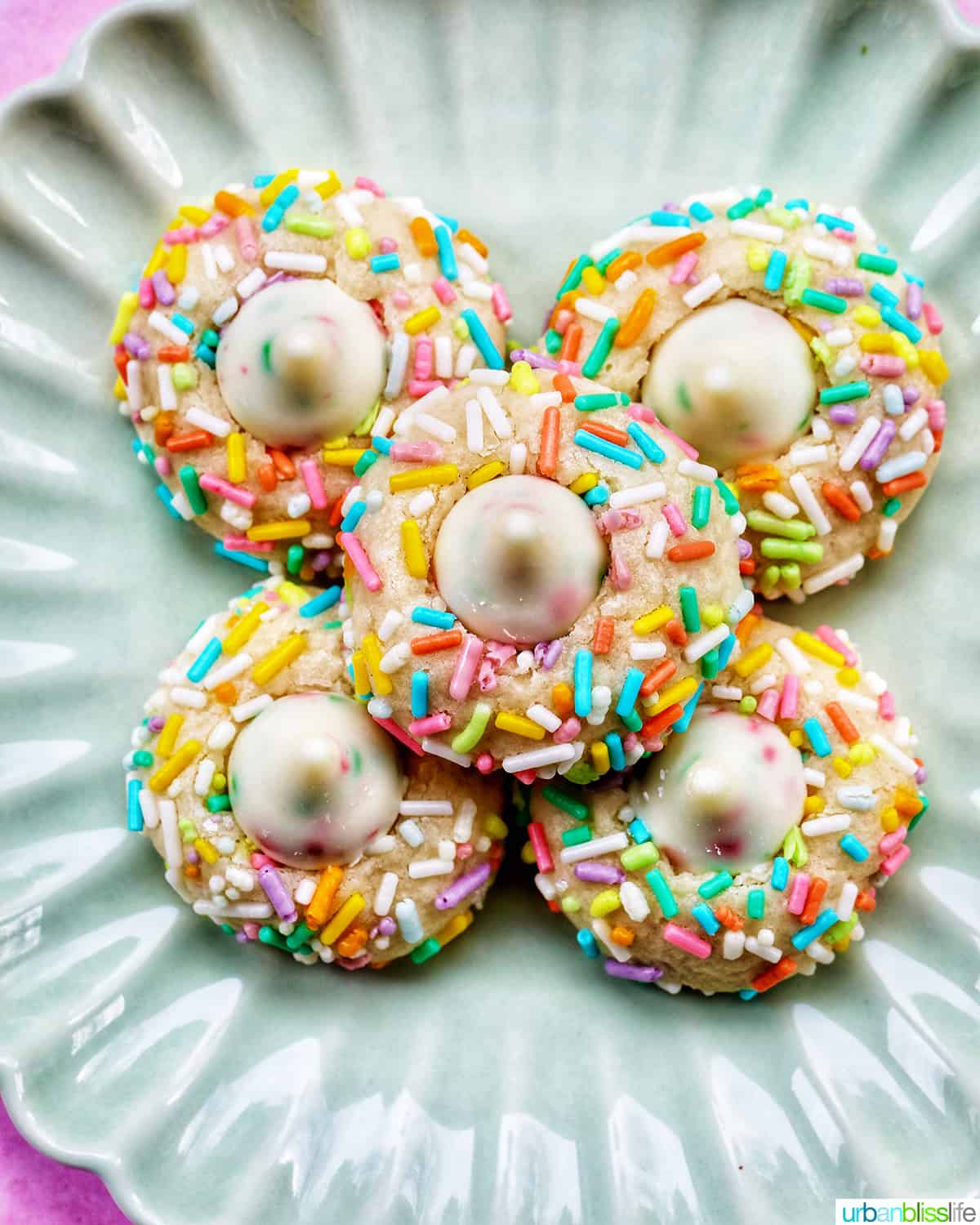 several spring almond sprinkle cookies stacked on top of one another.