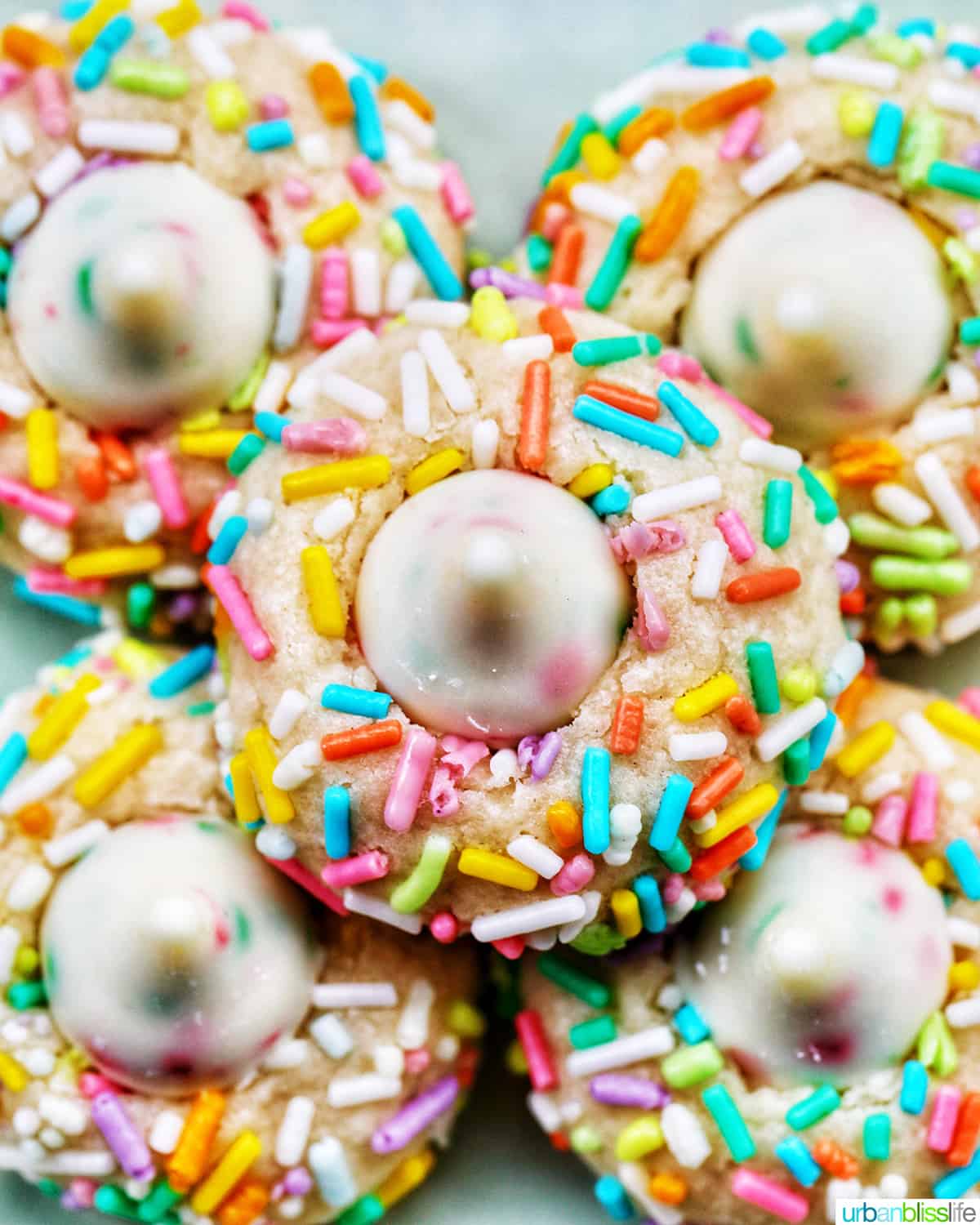 several spring almond sprinkle cookies stacked on top of one another.