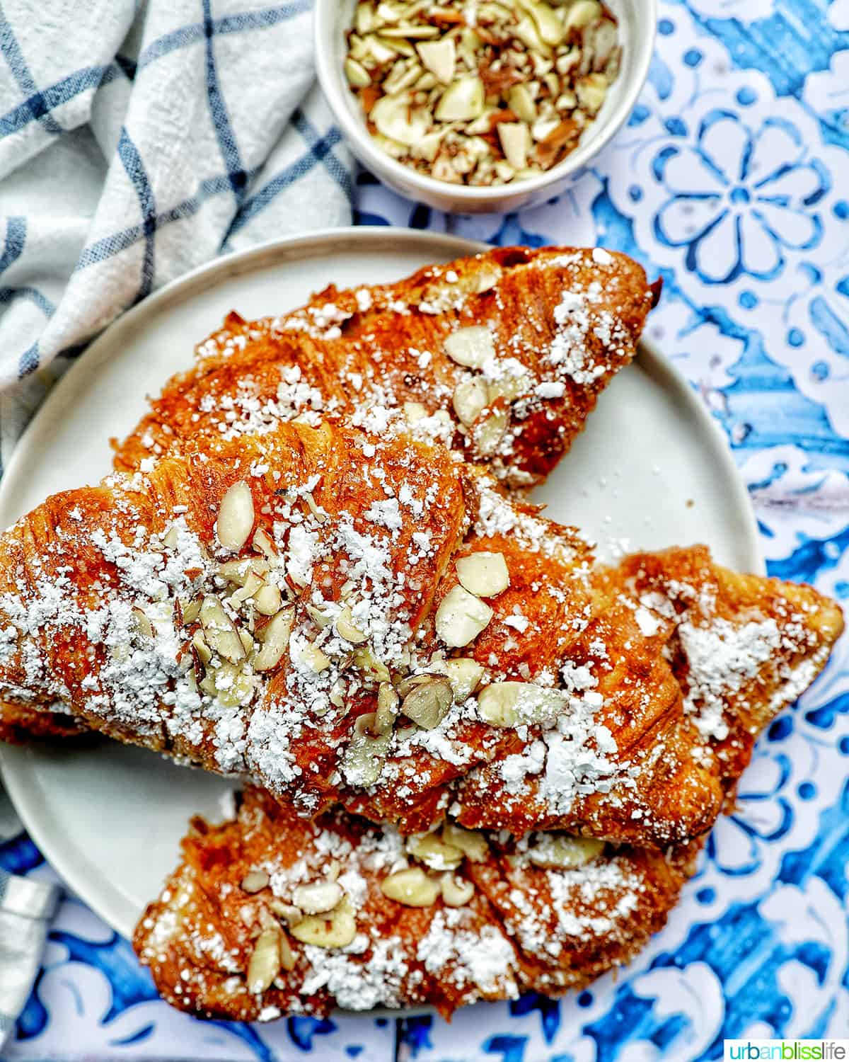 three almond croissants on a plate.