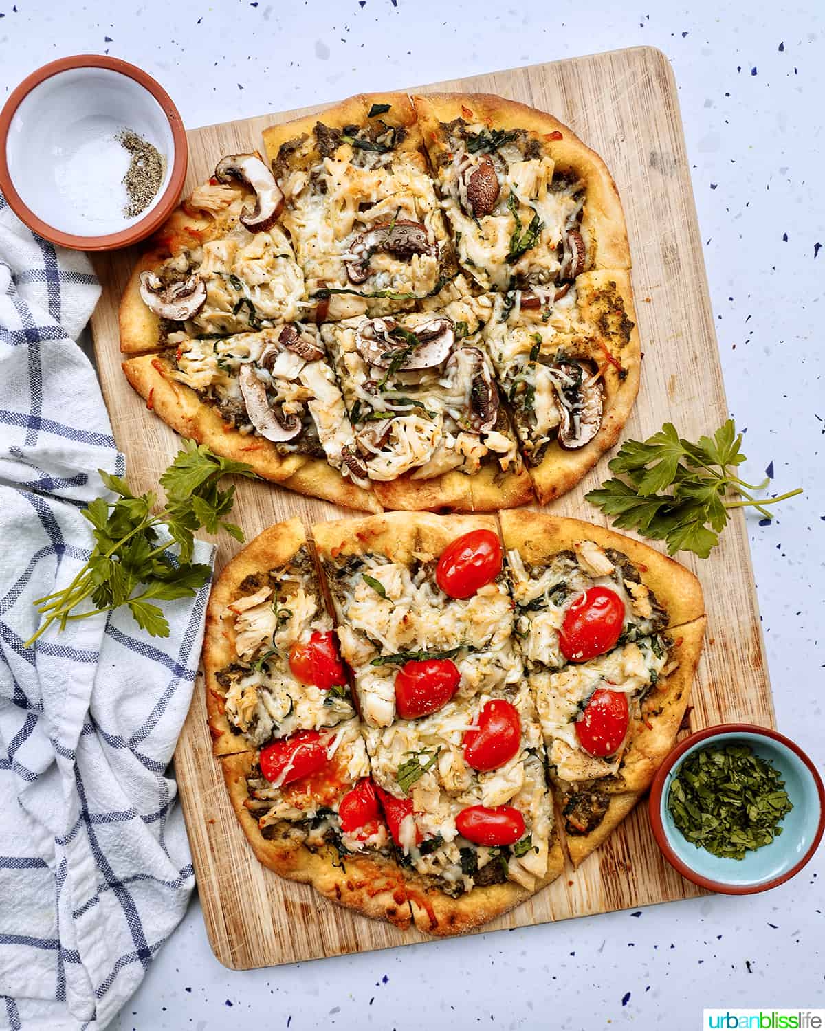 two chicken pesto flatbreads, one with tomatoes and one with mushrooms.