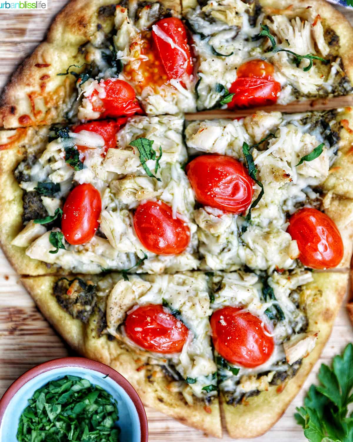 slices of chicken pesto flatbread on a wooden board.