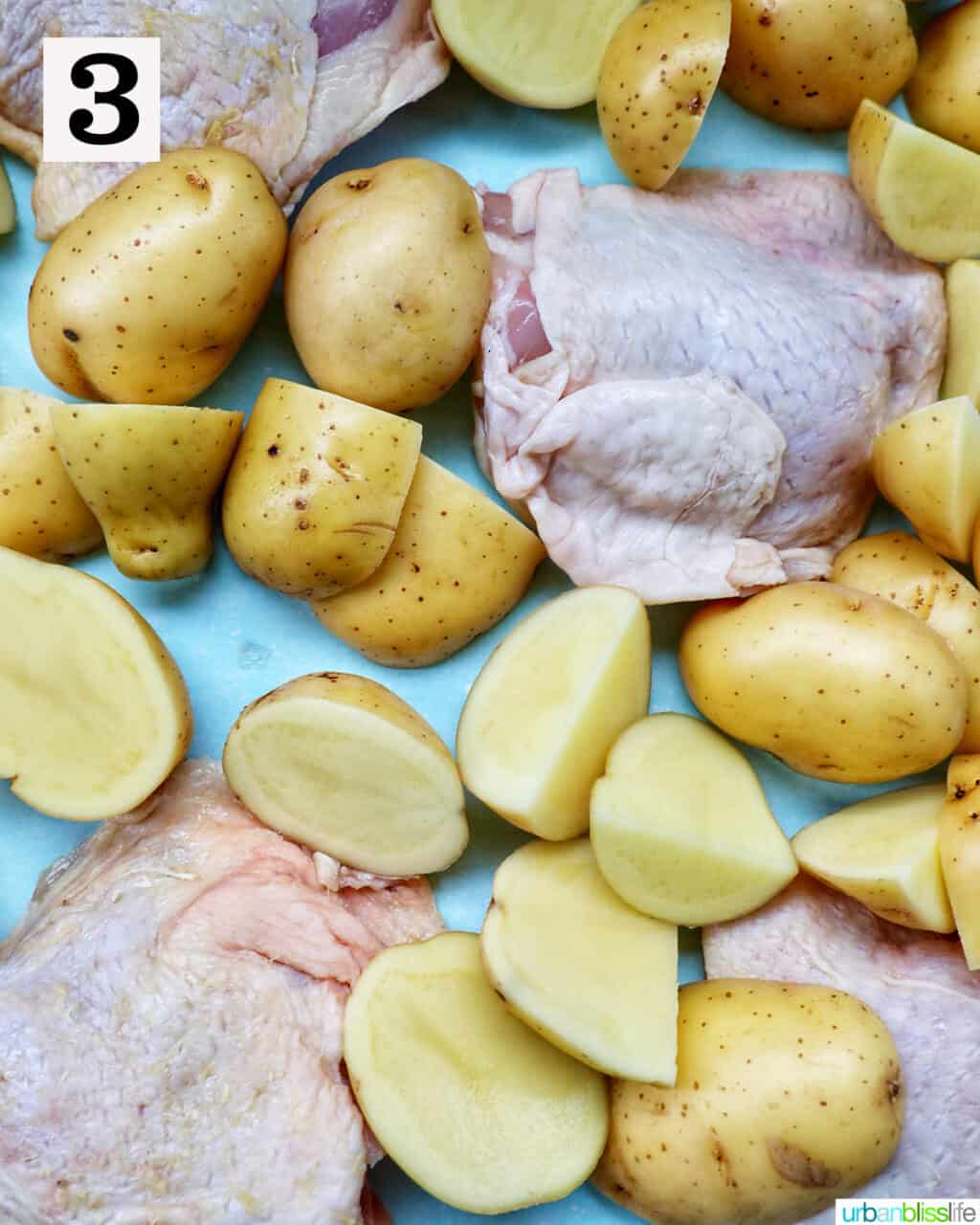raw chicken and baby potatoes on a sheet pan.