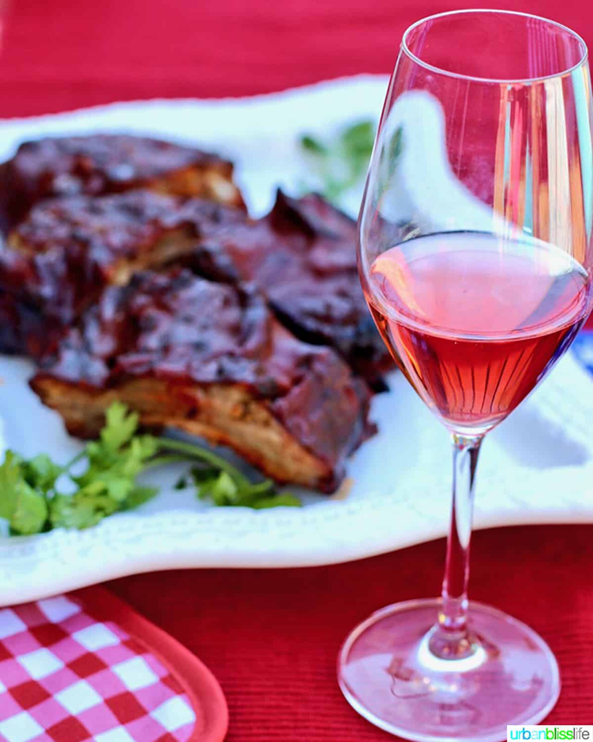 glass of rosé wine and plate of steak ribs.