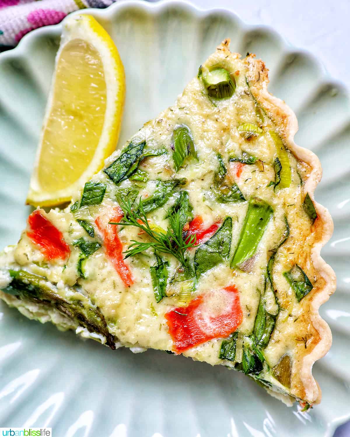 slice of salmon quiche with asparagus and leeks, and a slice of lemon on the side.