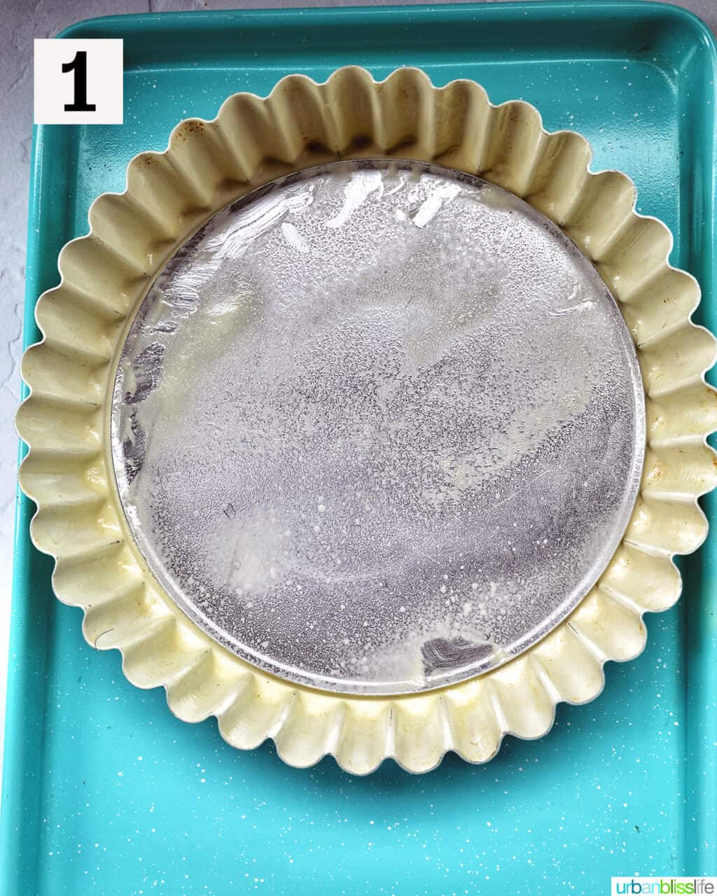 pie plate sprayed with baking spray on a blue baking sheet.