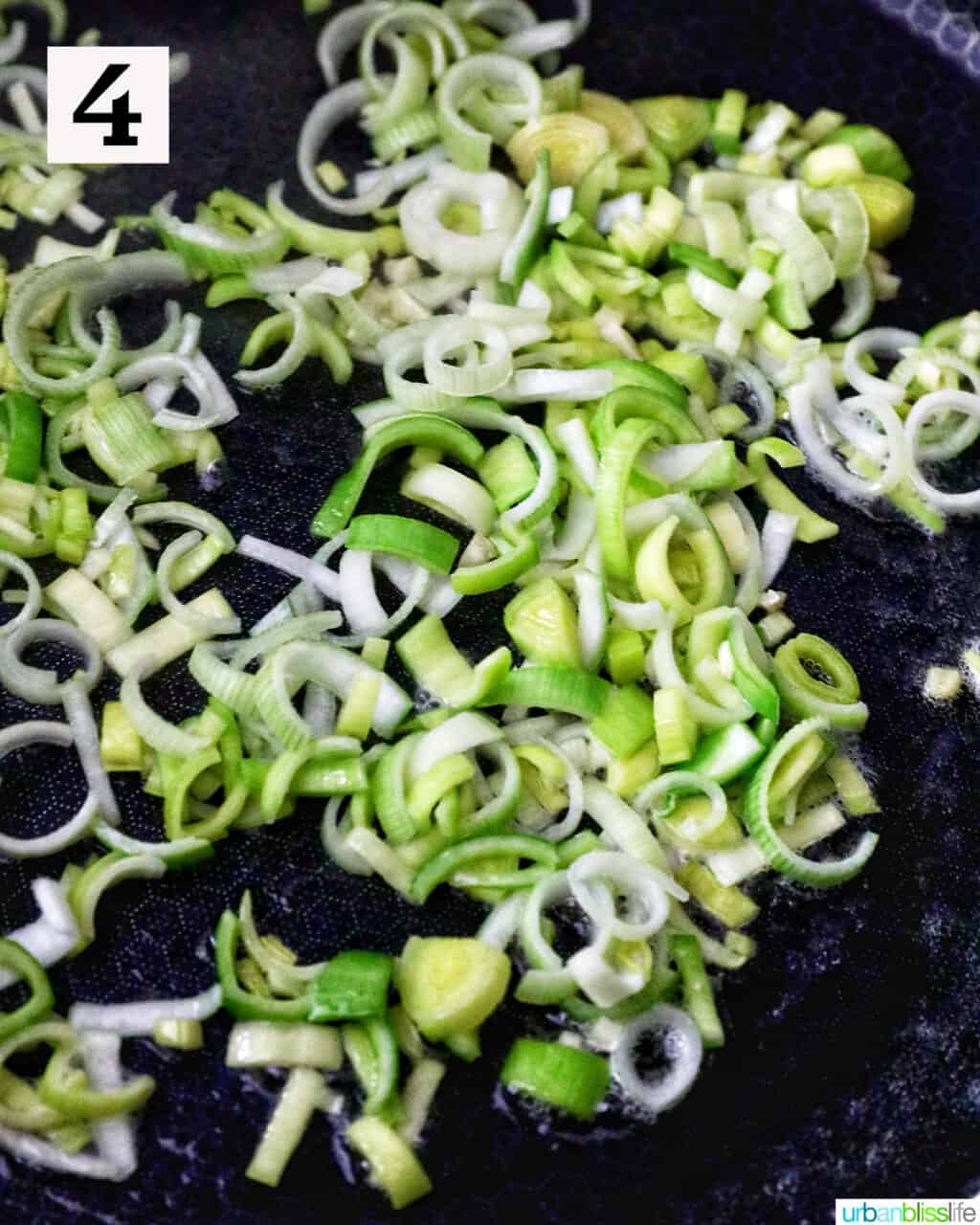 sliced leeks and garlic sauteing in a pan.