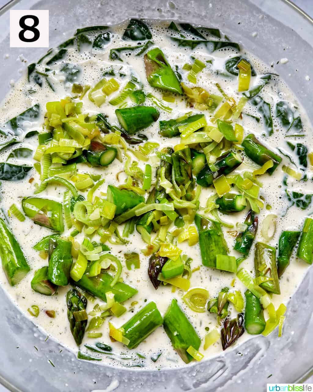 sliced asparagus and leeks in a quiche creamy filling in a bowl.