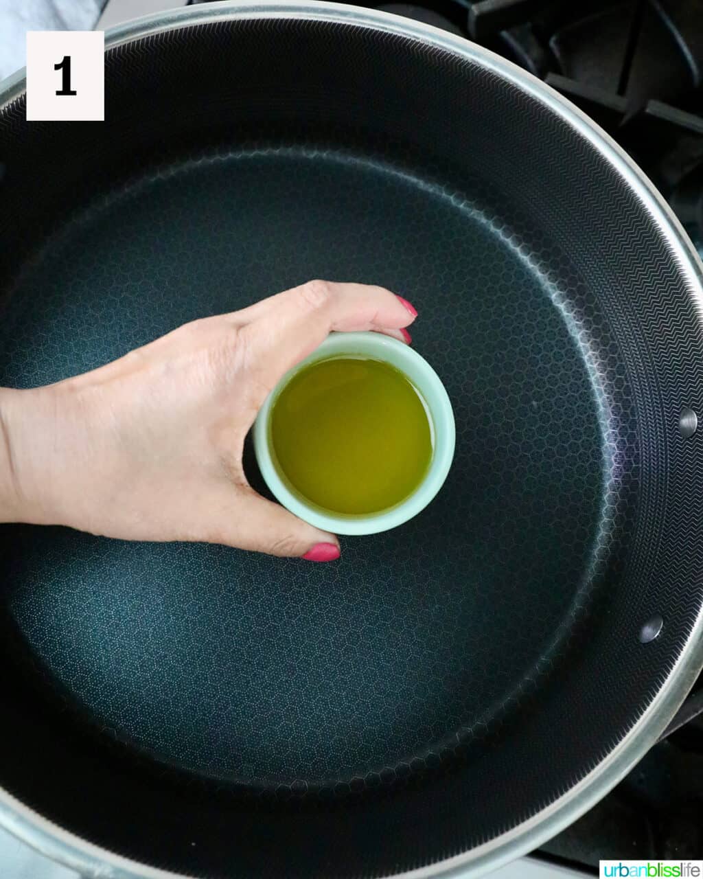 hand holding olive oil over a pan.
