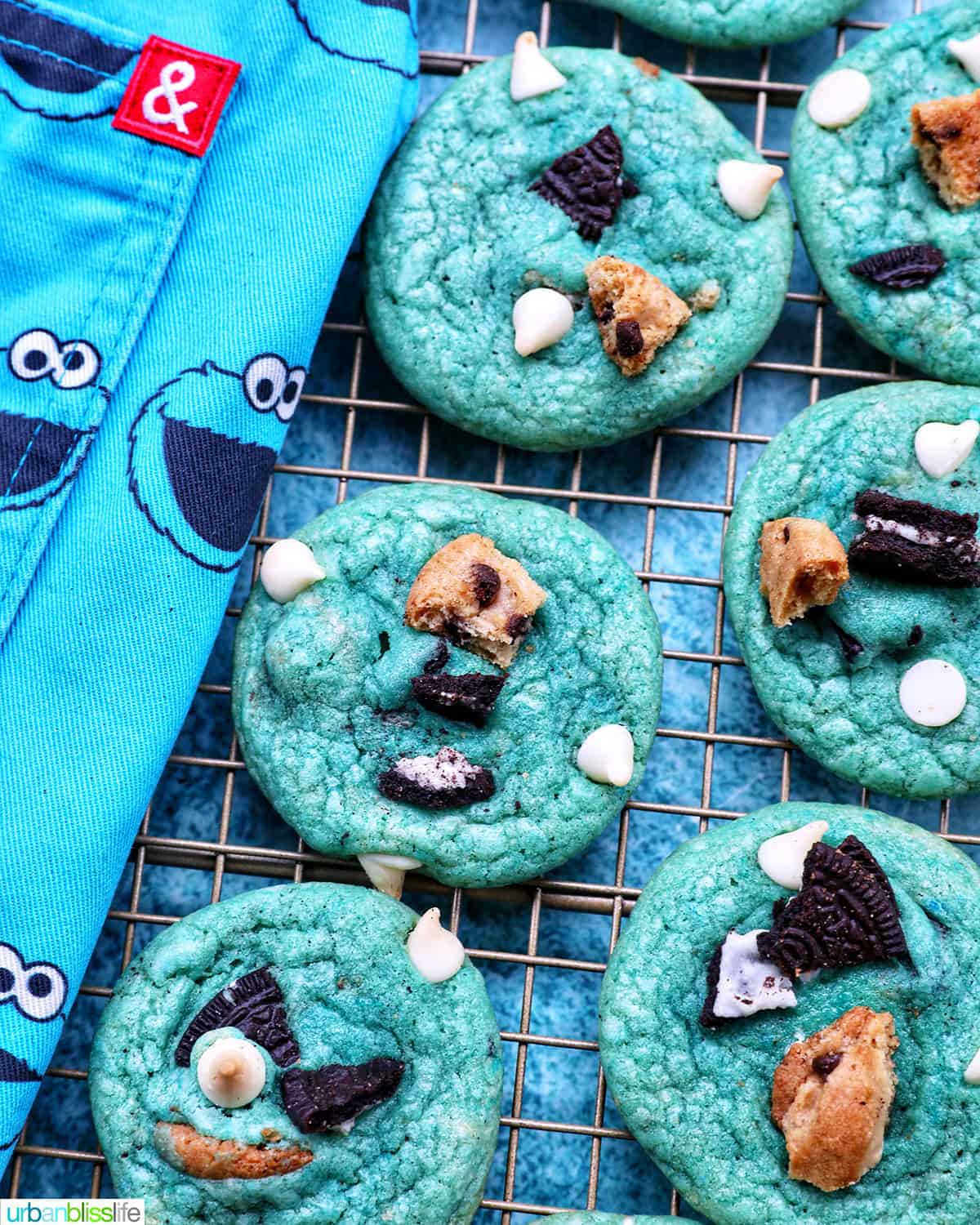 cookie monster cookies on a wire rack next to a cookie monster apron.