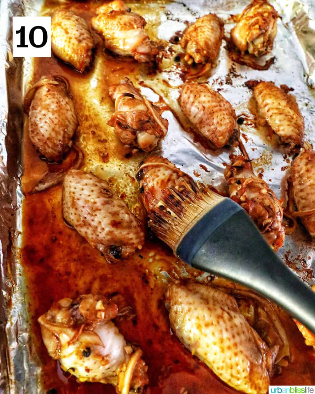 basting chicken wings with adobo sauce on a baking sheet.