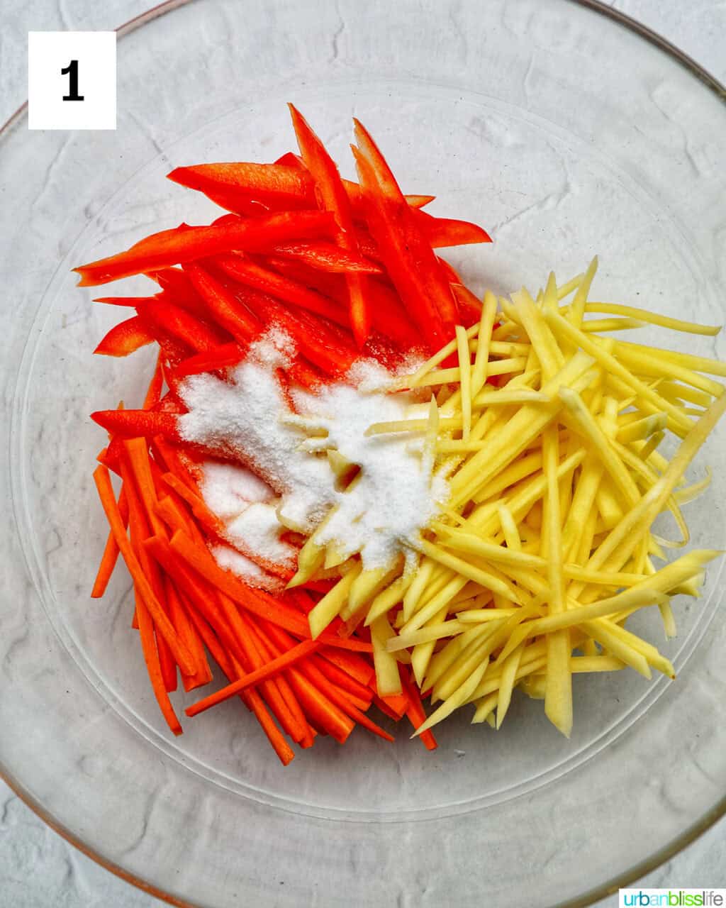 sliced papaya, carrots, red bell pepper in a bowl with sugar.