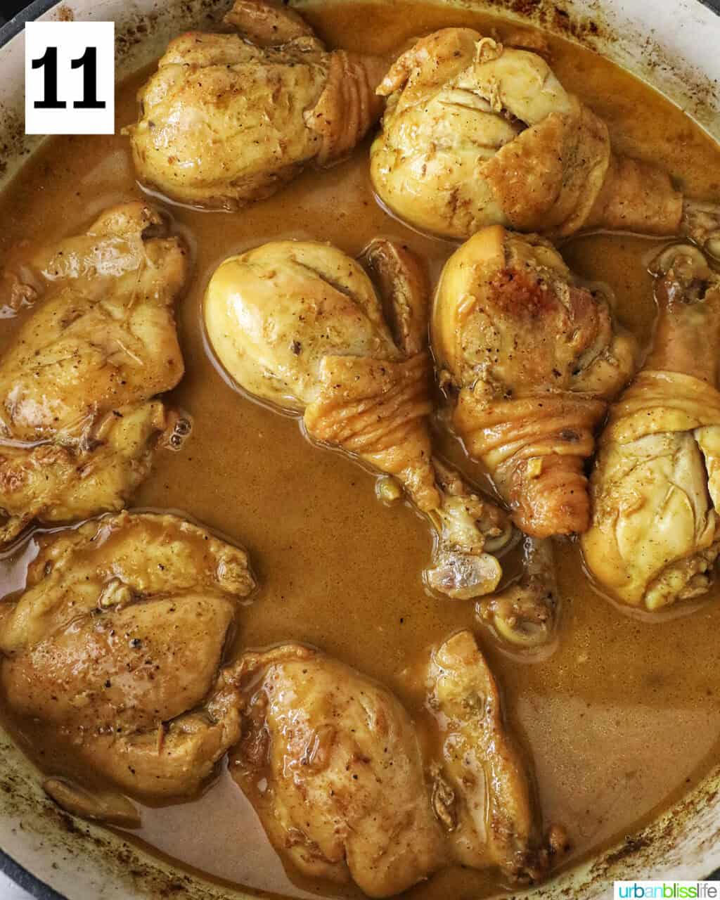 chicken cooking in curry sauce in a large pan.