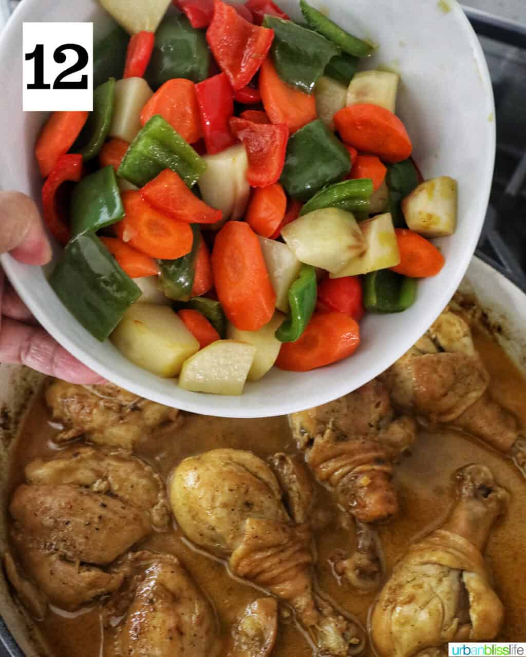 bowl of chopped vegetables over a pan of curry chicken.