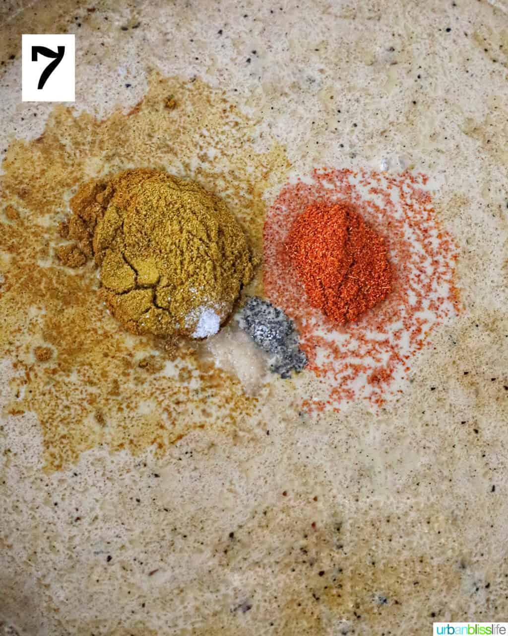 spices added to coconut milk in a large pan to make curry.
