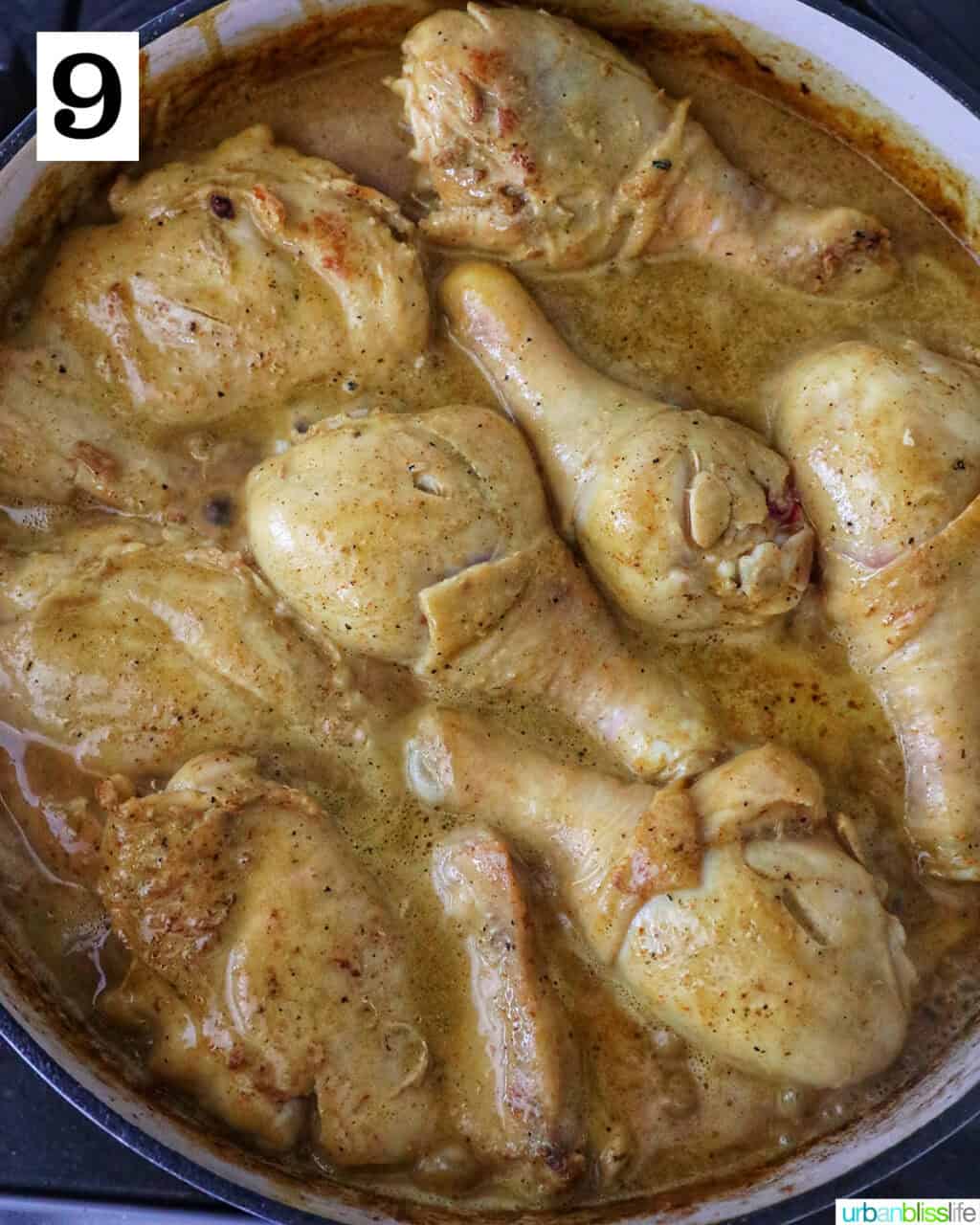 chicken cooking in curry sauce in a large pan.