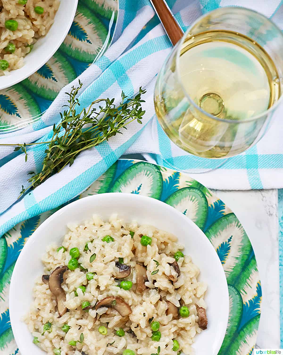 glass of white wine with bowl of mushroom risotto.