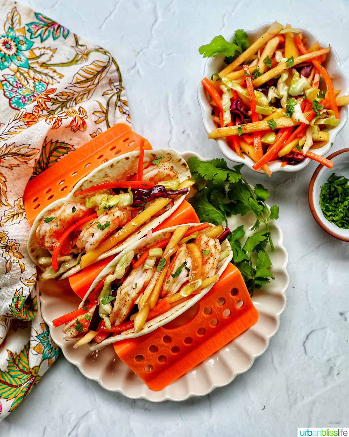 shrimp tacos on a plate with a side of mango slaw.