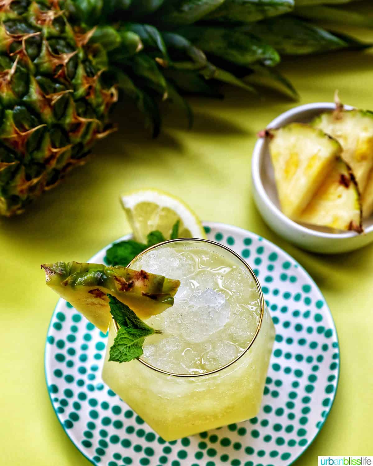 pineapple mocktail in a glass with pineapple and slices of pineapple on the side.