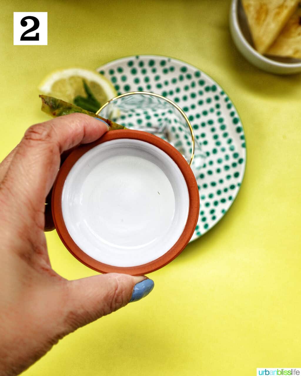 hand holding a bowl of simple syrup over a glass.